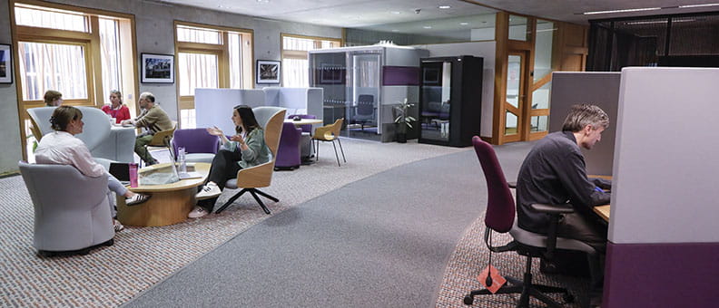 A breakout area with different seating options. Staff are working or having meetings in this area.