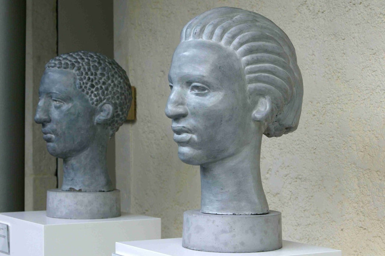 Three busts of human heads made of concrete. 